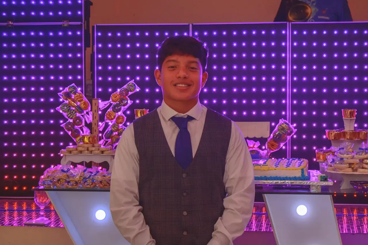 El quinceañero de pie frente a las letras de XV años