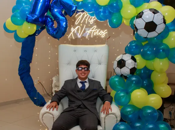 El quinceañero sentado en una silla decorada de XV años